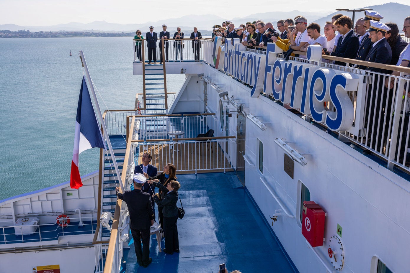 El capitán, el presidente de Brittany Ferries y las autoridades francesas izan la bandera en presencia de la tripulación.