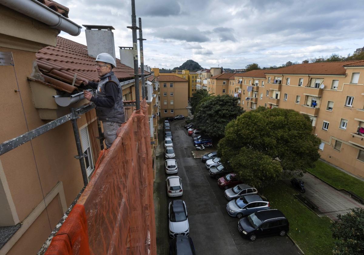 Un albañil revisa el tejado en unas obras de rehabilitación en Santander, en las viviendas de la Renfe en Cajo.