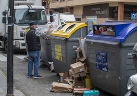 Un hombre tira plástico en el contenedor amarillo en una calle de Maliaño durante la huelga de basura.