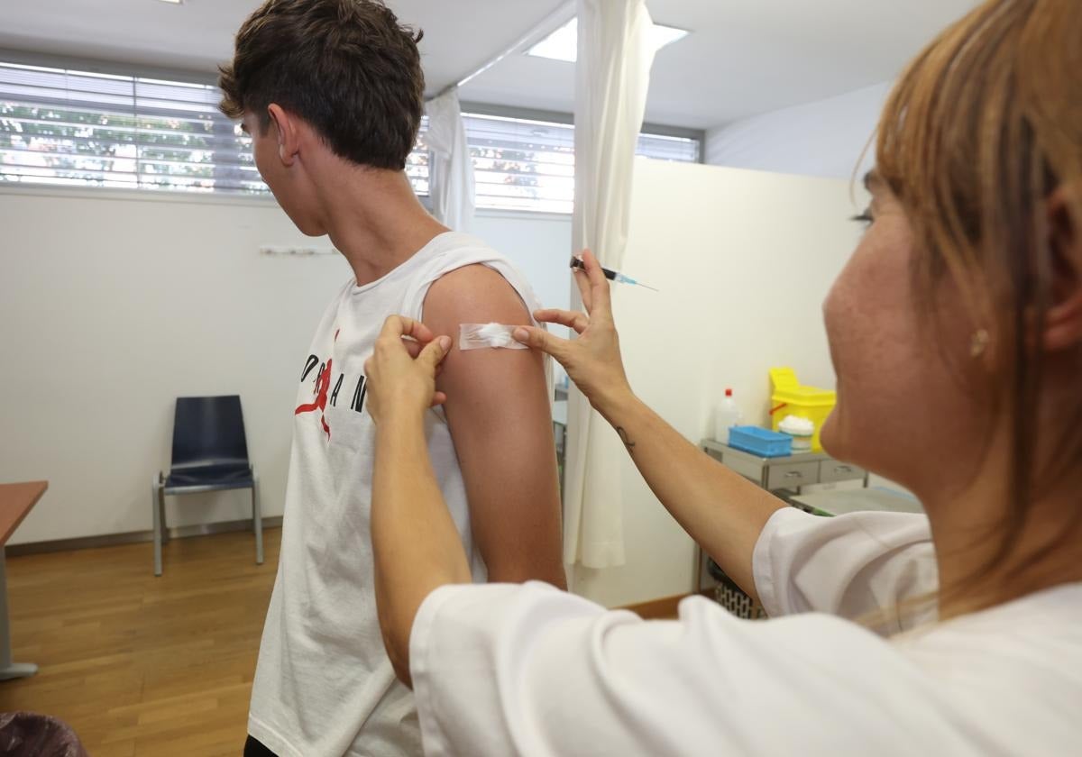 Una enfermera coloca una tirita a un joven tras administrarle la vacuna frente al virus del papiloma humano.