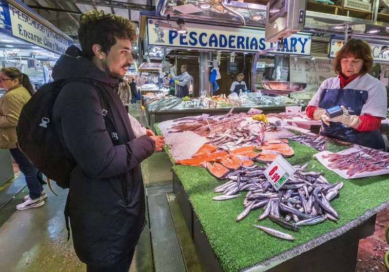 Un joven comprando bocartes en una pescadería del Mercado de la Esperanza.