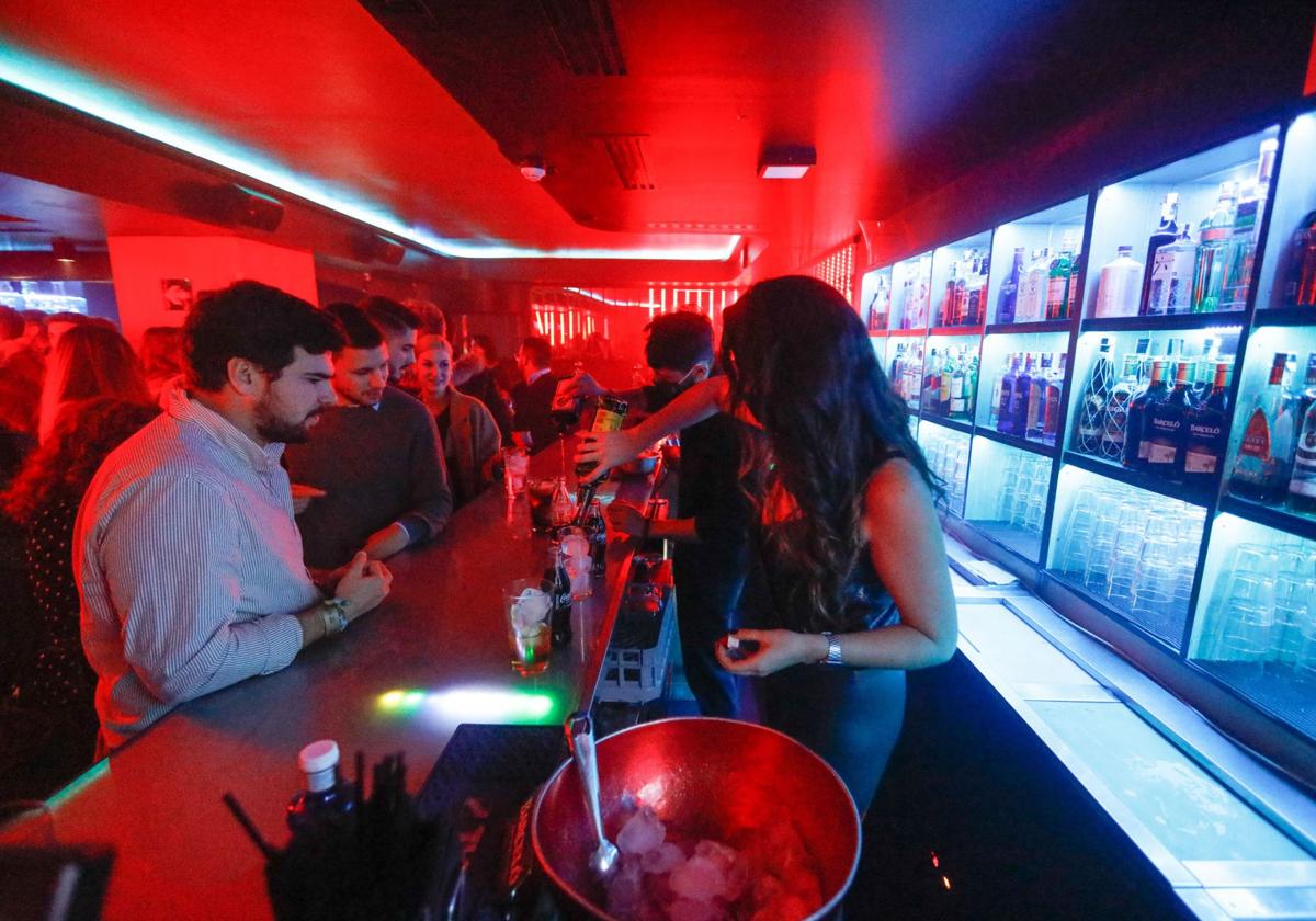 Una camarera sirve unas copas a un grupo de jóvenes en el interior de una discoteca, en una imagen de archivo.