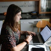 Una mujer teletrabaja con su ordenador desde su cocina.
