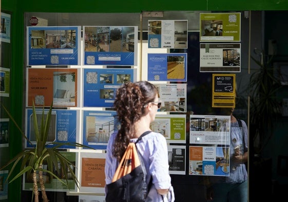 Una mujer mira anuncios de una inmobiliaria.