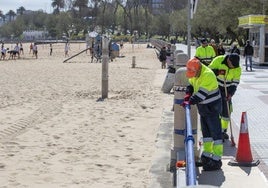 El servicio municipal de mantenimiento de playas lija las vallas de El Sardinero para repintarla.