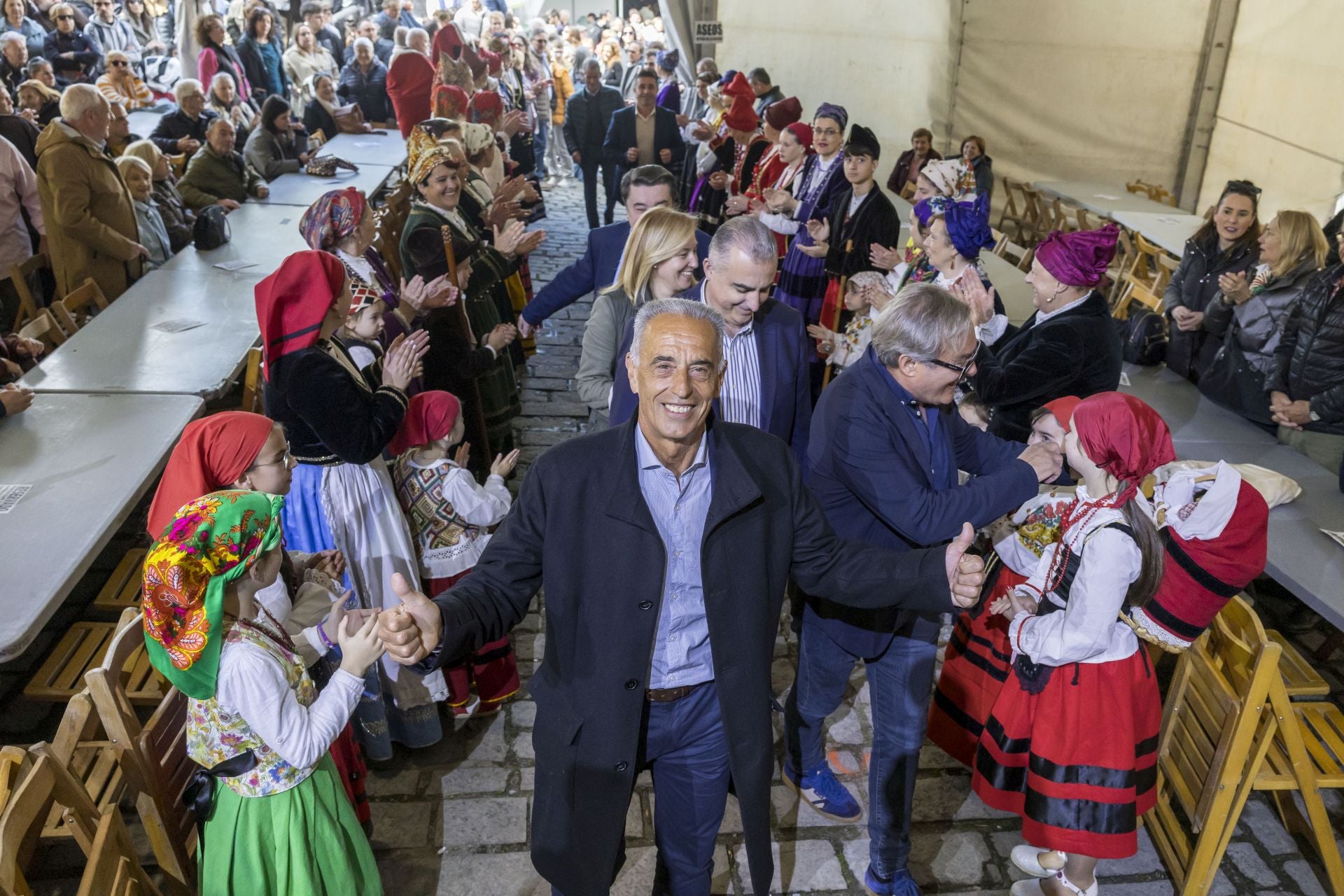 L﻿as mujeres de la Asociación Mujeres Río Aján reciben al ex atleta y medallista olímpico, José Manuel Abascal, que llegó junto al alcalde de Vega de Pas, Juan Carlos García; el consejero de Fomento, Roberto Media; la presidenta del Parlamento, María José González Revuelta; y el presidente de la IGP del Sobao Pasiego, Adolfo Gómez.
