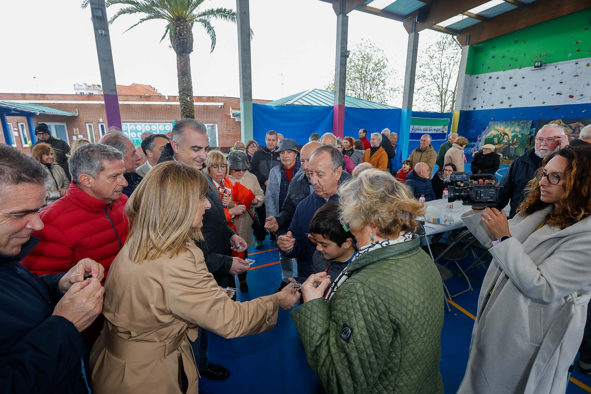 La presidenta repartiendo las insignias a las víctimas de esta situación, en la pista deportiva de Argoños. 