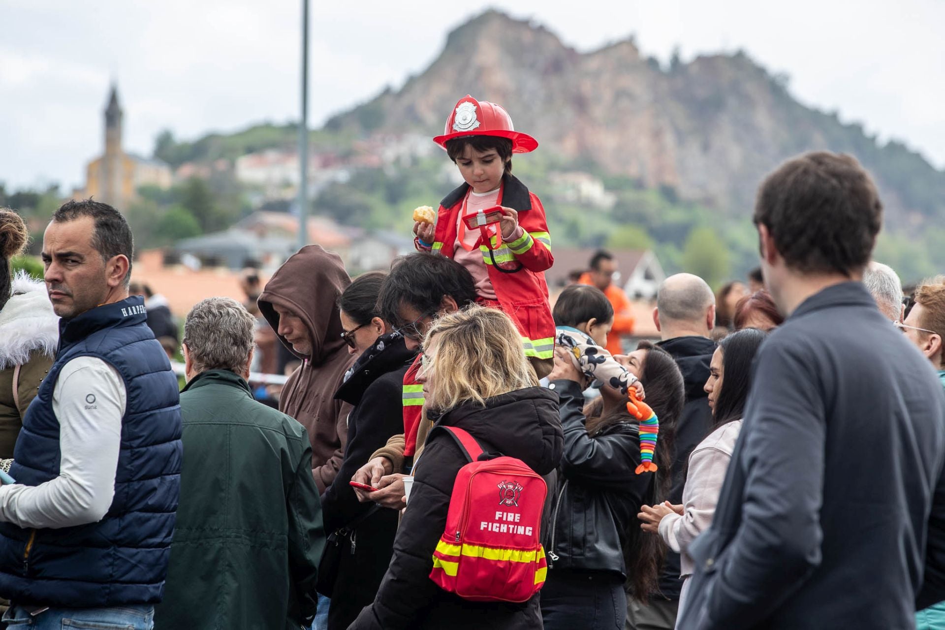 Un niño, ataviado con un traje de bombero, espera junto a su familia para ver una de las exhibiciones de maniobras que se realizaron.