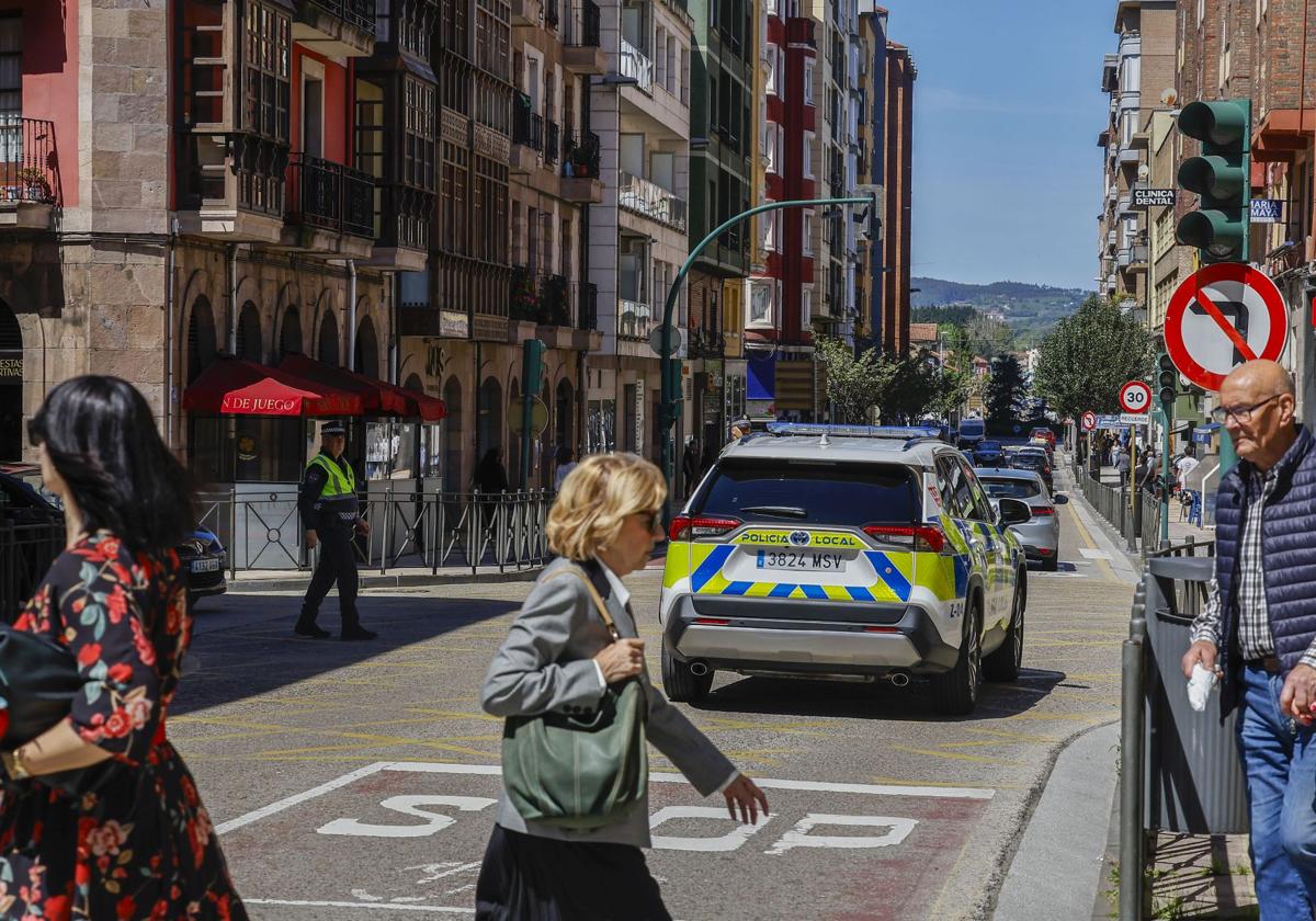 Vecinos cruzan la calle frente al cruce de Cuatro Caminos, con la Policía Local gestionando el tráfico tras el apagón de los semáforos, en Torrelavega.