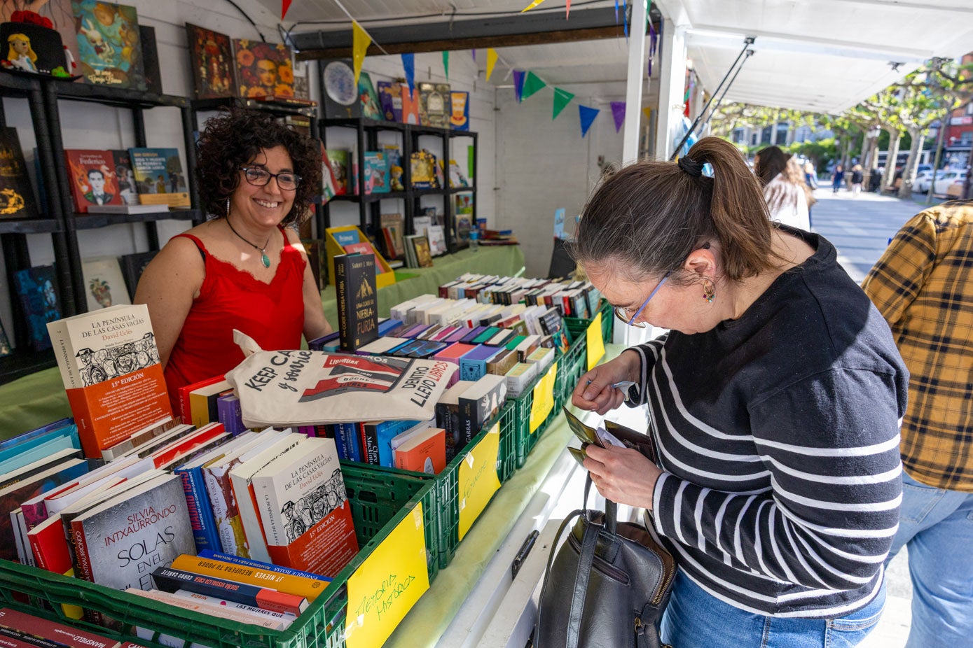 Una librera vende varios ejemplares a una clienta, este miércoles en su estand