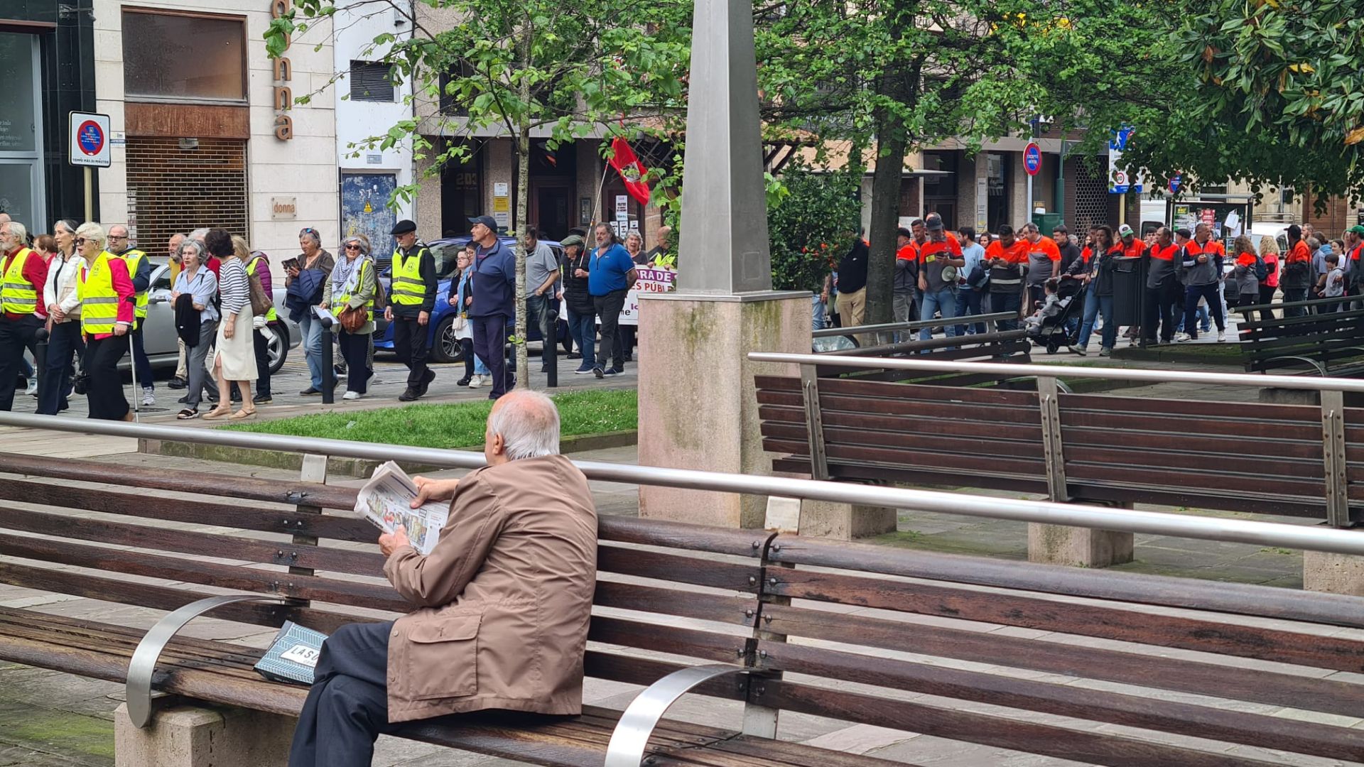 Un vecino se interesa por la movilización mientras lee el periódico en el entorno de La Asunción, este jueves, en Torrelavega. 