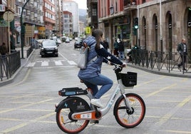 Una vecina circula con una bicicleta eléctrica de Torrelavega, en el cruce de Cuatro Caminos.
