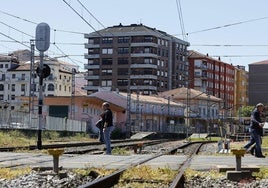 Vecinos cruzan el paso a nivel de Pablo Garnica, con la estación de tren Torrelavega-Centro al fondo de la imagen.