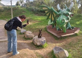 Una visitante realiza una foto a su perro con el culebre de fondo