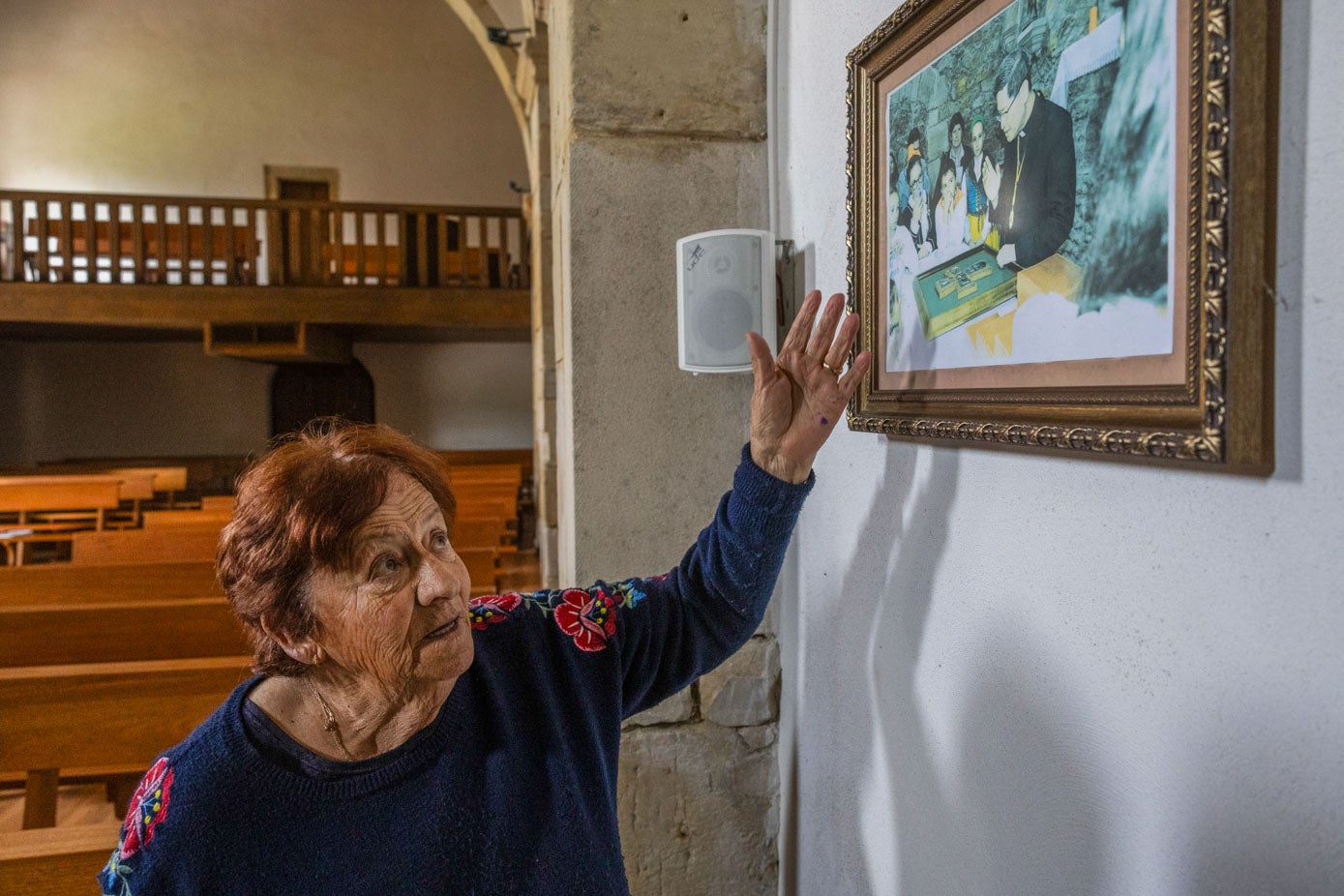 Fotografía colgada en la iglesia, algo descoloridad por el sol, en la que se ve al cardenal Tagle bendiciendo el cuadro con la cruz que donó Pilar Guerra.