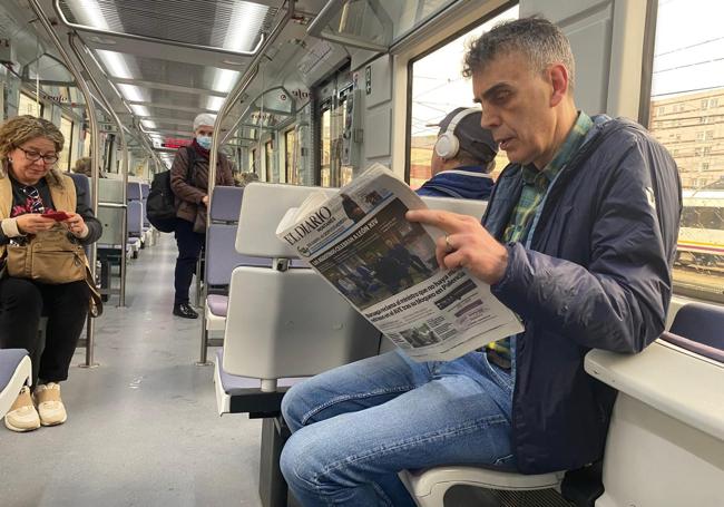 Un usuario lee El Diario Montañés mientras viaja en tren.
