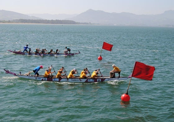 Los equipos Cantabria en Rosa y Estelas Rosas remando en sus barcos dragones en una de las tandas de regatas.