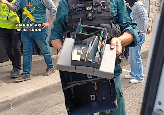 Un agente sostiene los restos de una de las cajas robadas en la gasolinera.