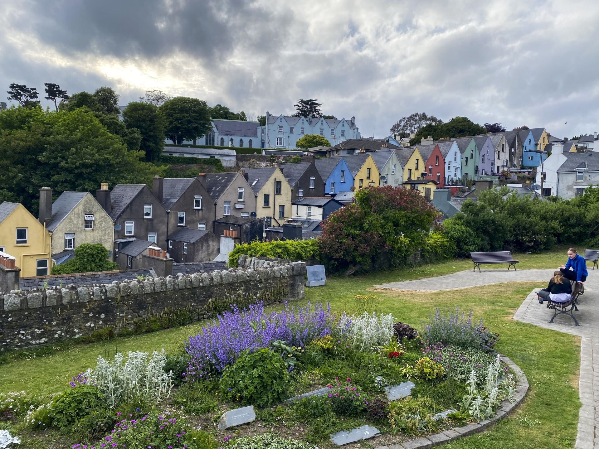 Dos jóvenes en un parque frente a las casas de colores en la localidad de Cobh.
