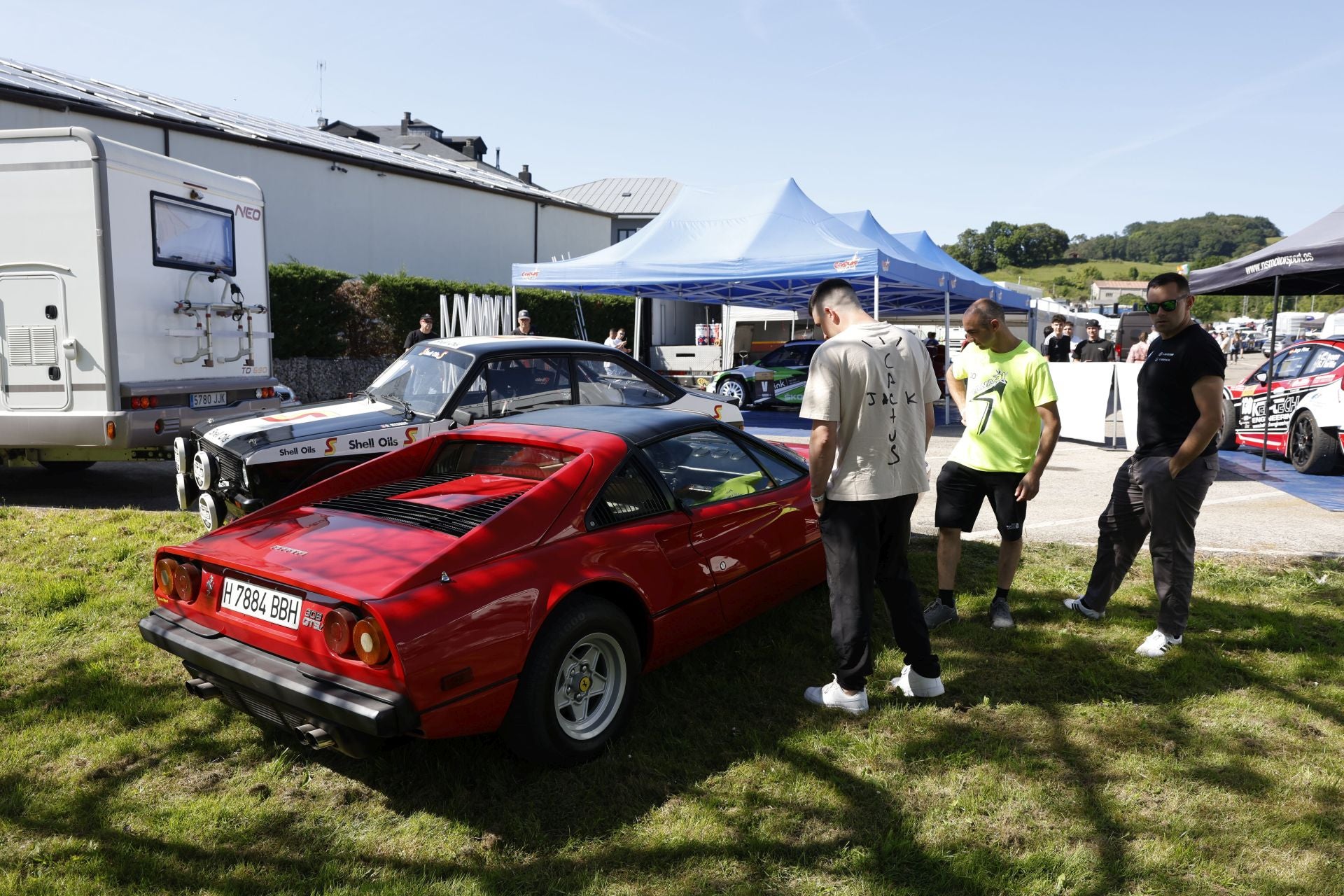 Tres aficionados contemplan un Ferrari 308 GTS.