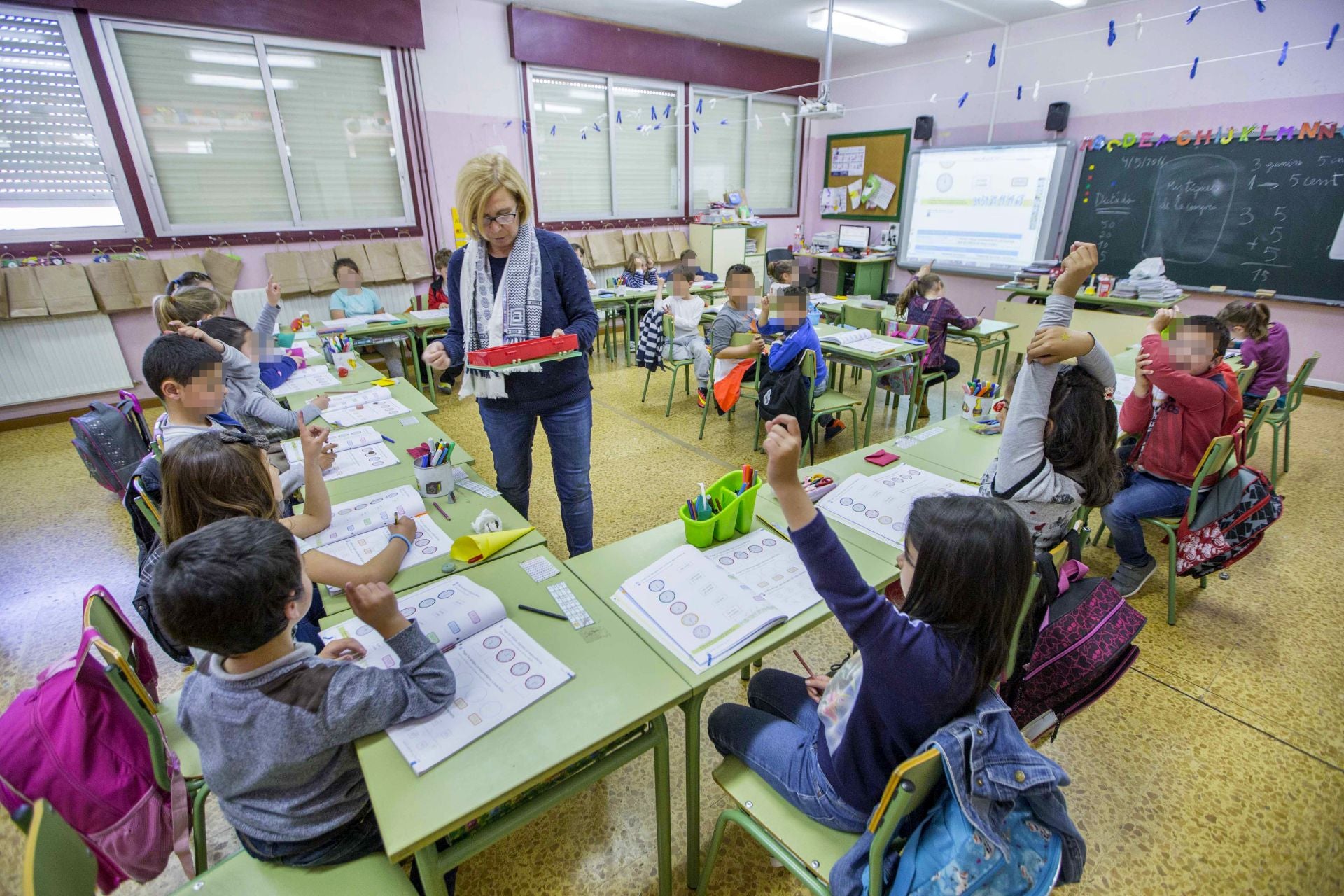 Una profesora de Cantabria reparte material a los alumnos durante una clase.