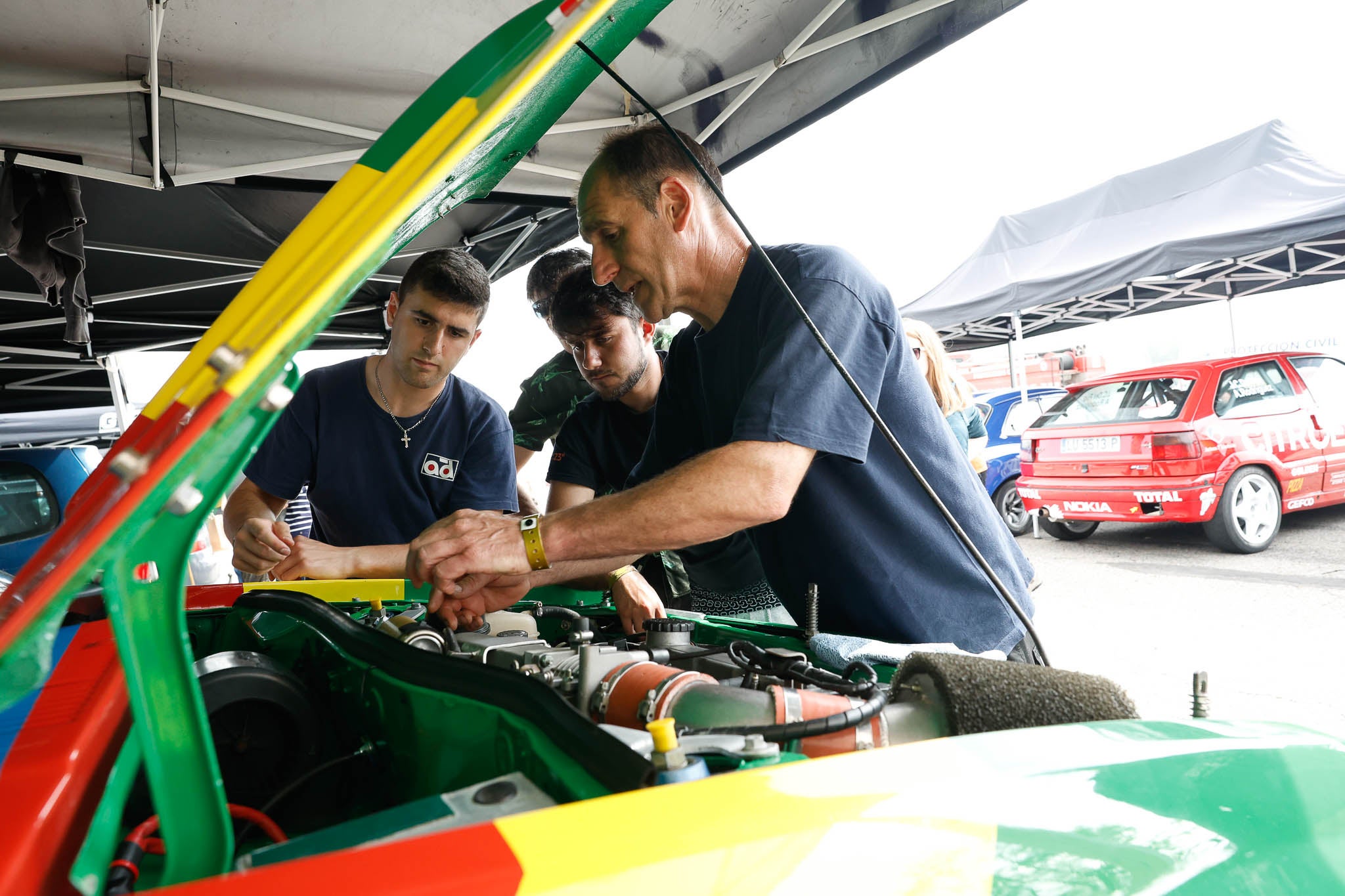 Tres mecánicos trabajan en el motor de un coche.