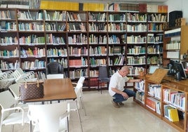 José Luis se agacha para alcanzar una de las estanterías de la biblioteca.