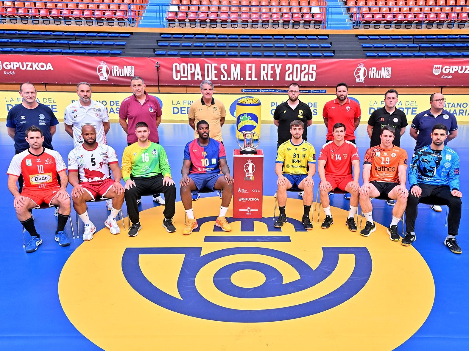 Los capitanes y entrenadores de los ochos equipos posan con el trofeo.