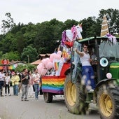 Uno de los tractores decorados como carrozas con una estela de público detrás.