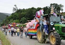 Uno de los tractores decorados como carrozas con una estela de público detrás.