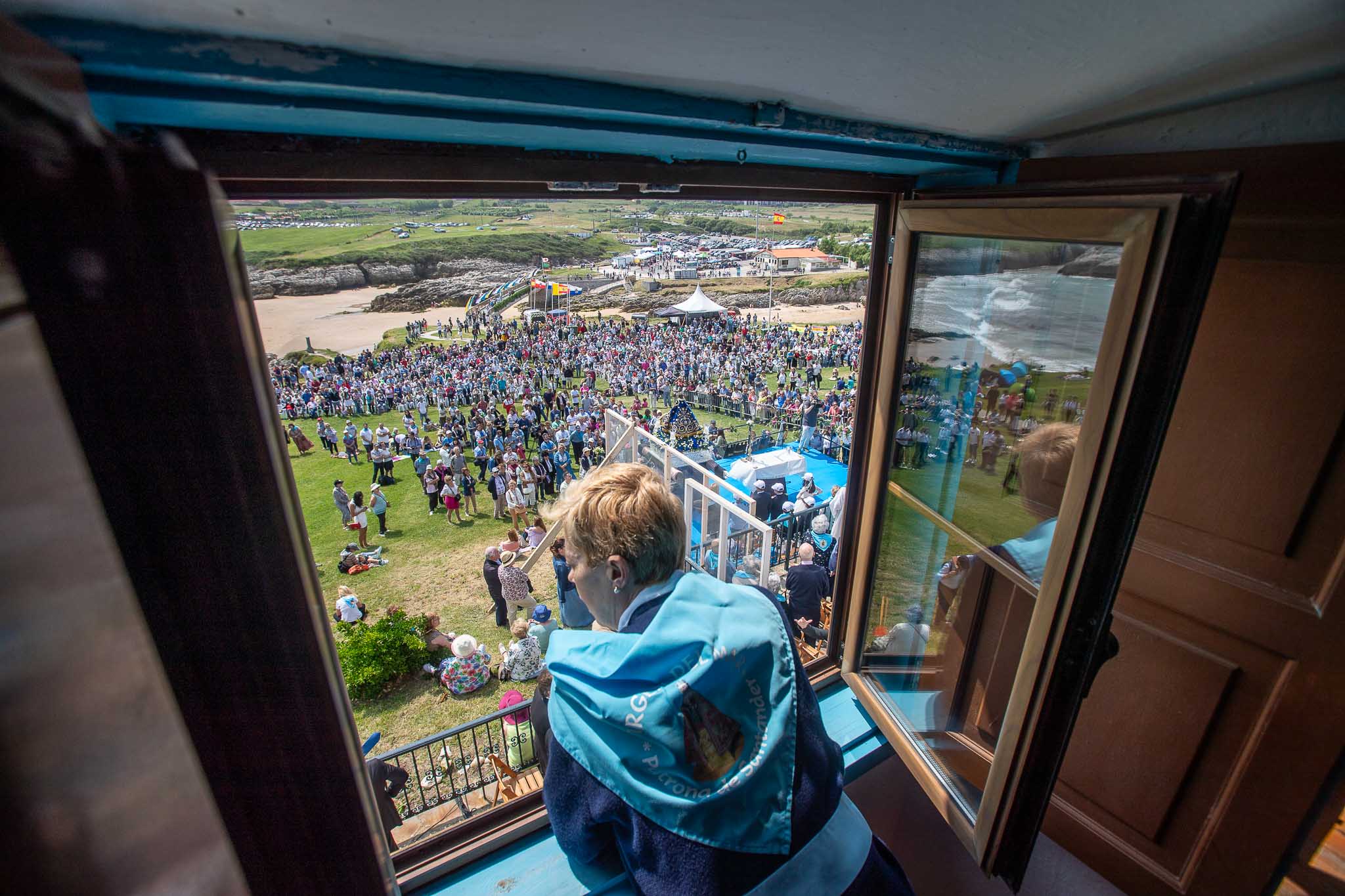 Una mujer se asoma a una ventana y observa la campa desde el interior de la ermita.