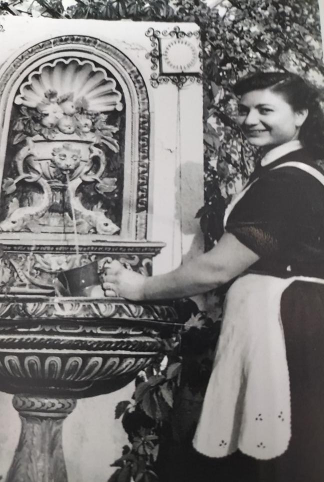 Natividad Martínez coge agua de una fuente en su época como empleada doméstica.