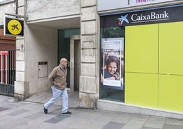 Un hombre pasea ante una oficina de Caixa.