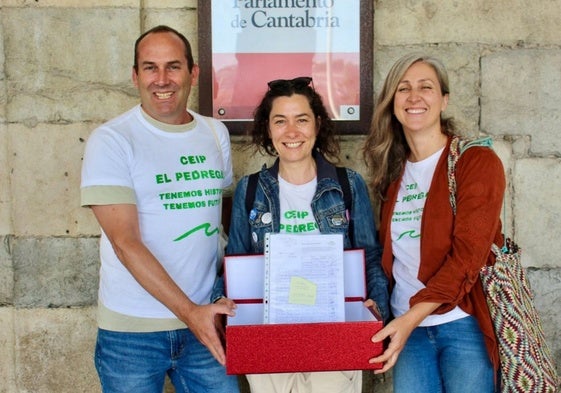Tres de los padres afectados por el futuro cierre del centro educativo con las firmas que han presentado en el Parlamento.