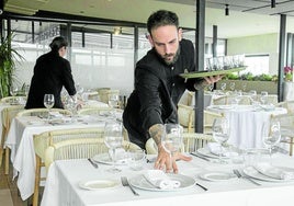 Profesionales de hostelería preparando un comedor para el servicio.