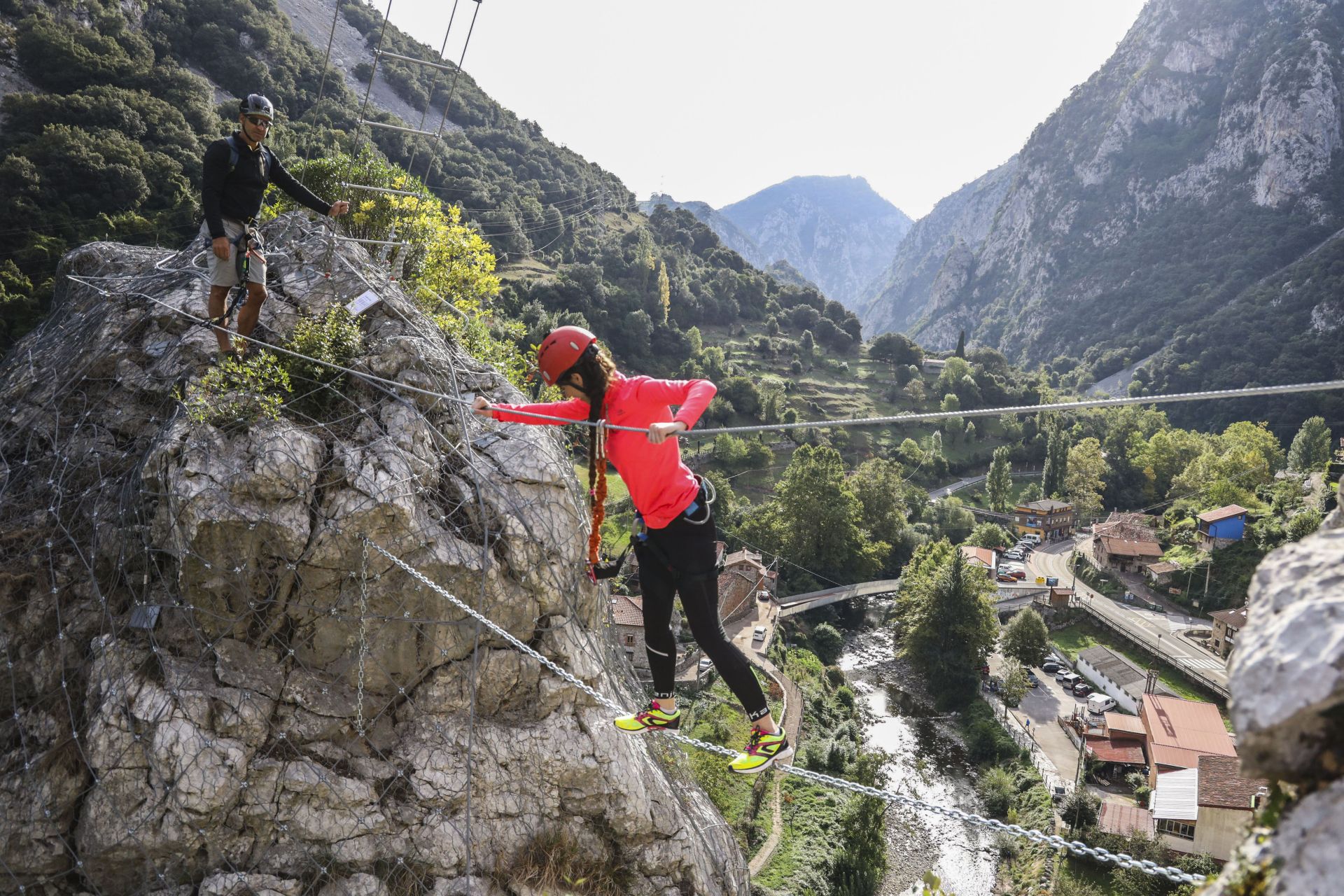 Una mujer cruza un puente tibetano, uno de los pasos más famosos de la vía ferrata de La Hermida, en el municipio de Peñarrubia.
