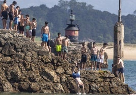 Varios jóvenes hacen cola, ayer, sobe el espigón de la playa de Bikinis, en Santander