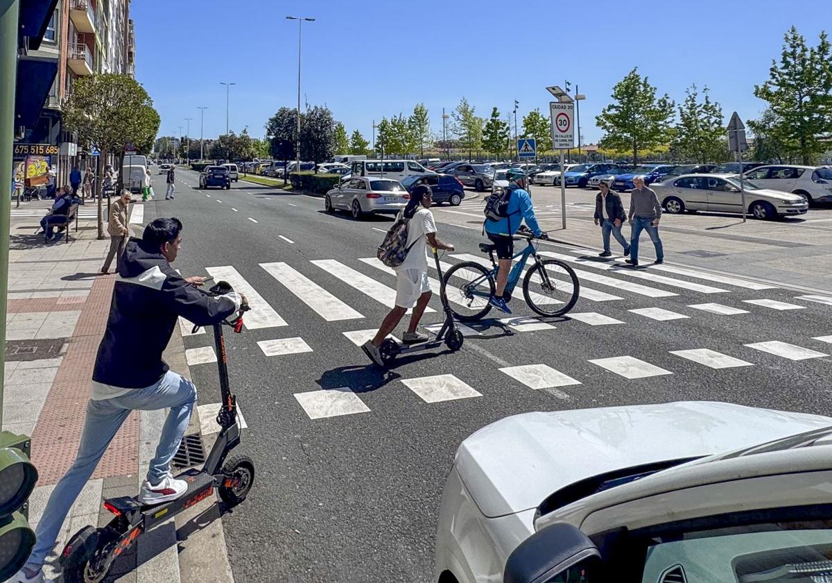 Varios usuarios de patinetes y bicicletas cruzan por un paso de peatones de Marqués de la Hermida.