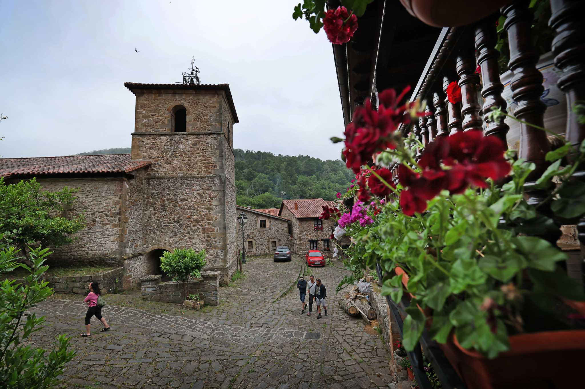 Plantas y colorido en los balcones de las casonas, con la iglesia de Santa María al fondo.