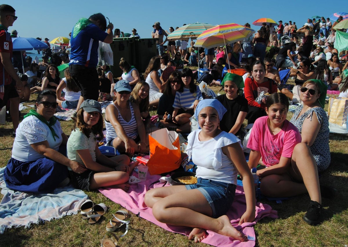 Imagen secundaria 1 - Un joven intenta cruzar la cucaña desde un muelle abarrotado de público expectante y grupos de niños y familias en la merienda de San Pelayo.
