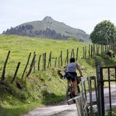 Un ciclista circula por la sierra del Dobra; al fondo, el pico de la Capía.