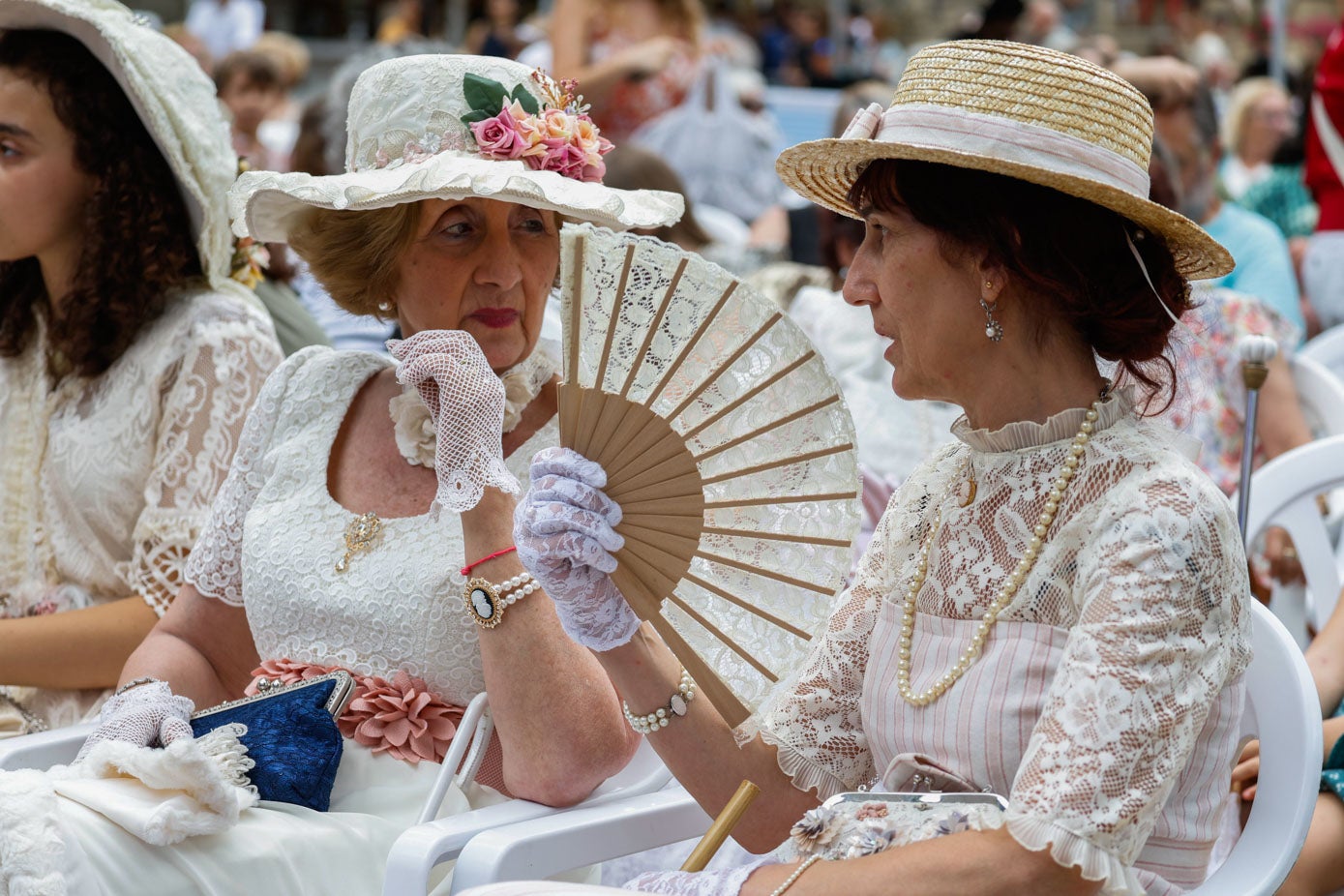 Dos participantes charlan, con sus sombreros y abanicos a gala -hizo bastante calor este domingo-.