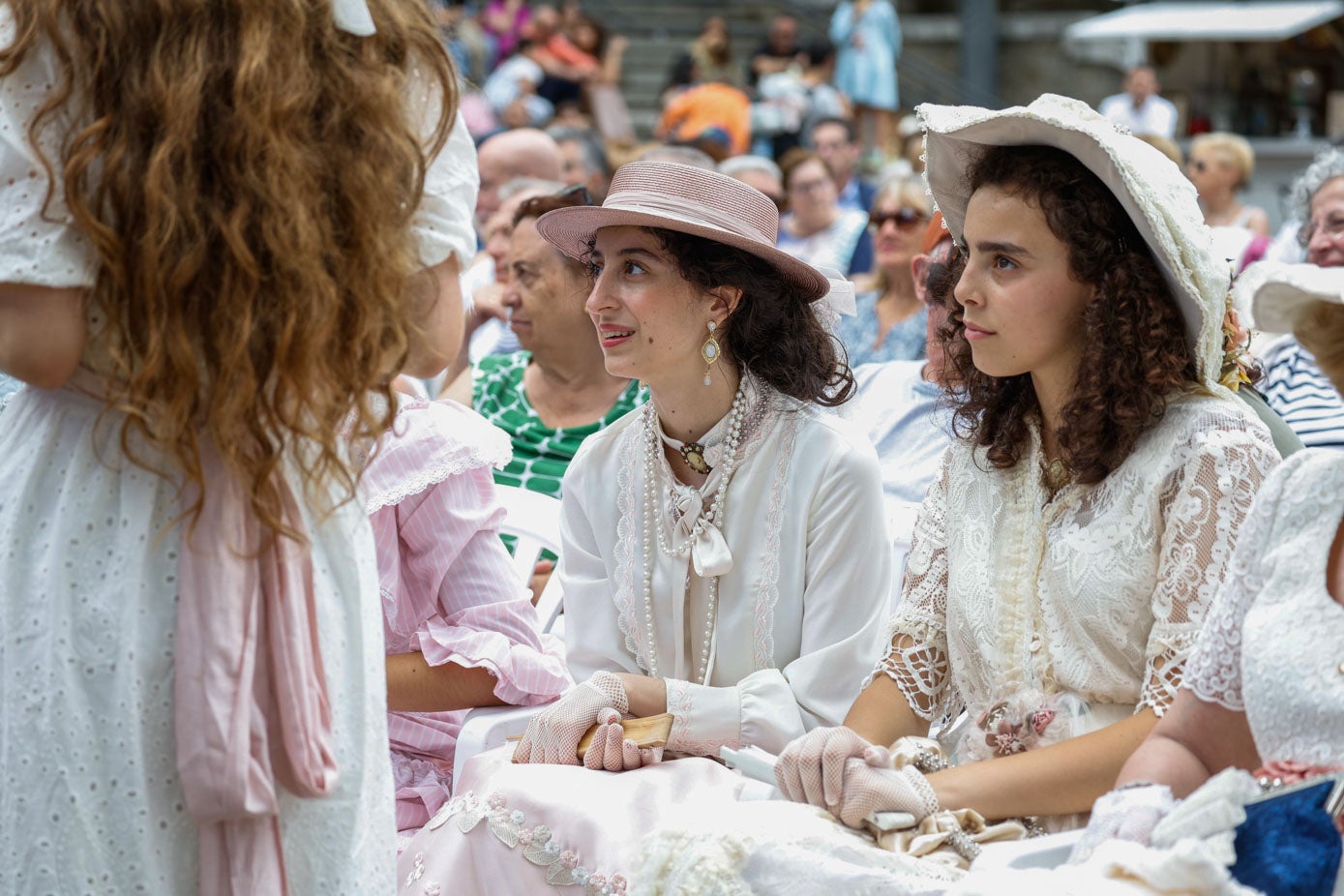 Dos jóvenes atienden durante la presentación de los vestidos y los trajes sobre el escenario, ayer, en Santander.