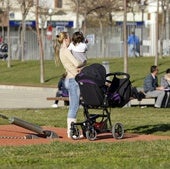 Una mujer con su bebé en brazos, en un parque.
