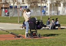 Una mujer con su bebé en brazos, en un parque.