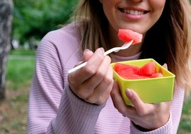 Una joven tomando sandía, una fruta muy estival.