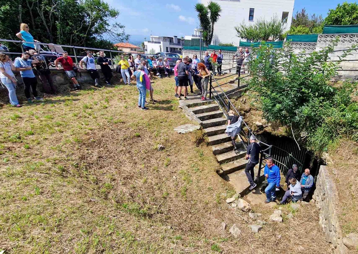 Imagen secundaria 1 - Arriba, mano en positivo en una imagen de Caeap, debajo el público esperando y uno de los turnos saliendo de la cavidad con Ramón Montes a la cabeza y de guía.