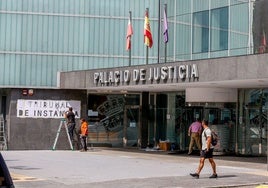 Dos operarios colocan el nuevo letrero de Tribunal de Instancia en el Palacio de Justicia de Torrelavega.