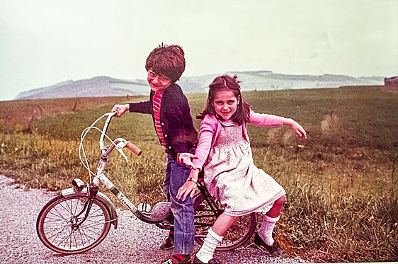 Baltasar Rodero, en la bici, con su hermana Lucía en la zona de Langre cuando eran pequeños.