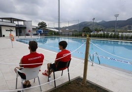 Dos socorristas junto a la piscina cerrada este domingo.